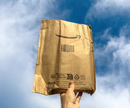 Hand holding Amazon cardboard package outdoors Stock Photos