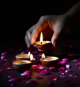 Hand holding and arranging lantern (Diya) during Diwali Festival of Lights Stock Photos