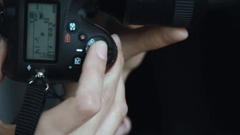 Hand holding and setting up a digital SLR camera. Close up of photographer hands Stock Footage 91076572