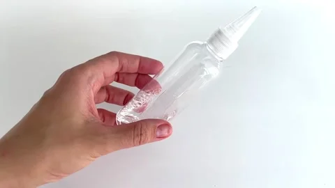 Hand holding and shaking transparent bottle with small amount of water Stock Footage 312622100