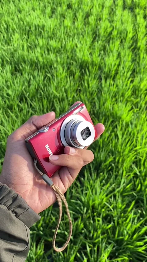 Hand holding and turning on a red digital camera Stock Footage 295011766