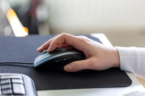 A hand holding and using an optical computer mouse to navigate on screen. The Stock Photos