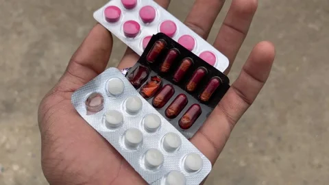 Hand Holding Assorted Medicine Tablets and Capsules in Blister Packs Stockbeeldmateriaal 327957329