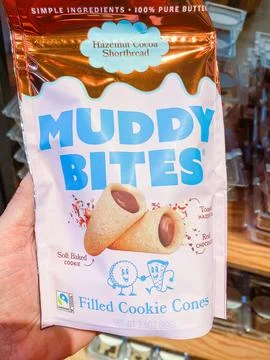A hand holding a bag of Muddy Bites hazelnut cocoa shortbread filled cookie.. 스톡 사진