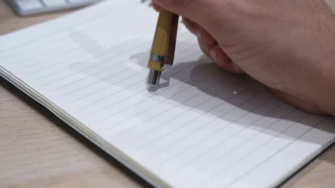 Hand Holding Bamboo Pen Over Blank Notebook Stock Footage 332628544