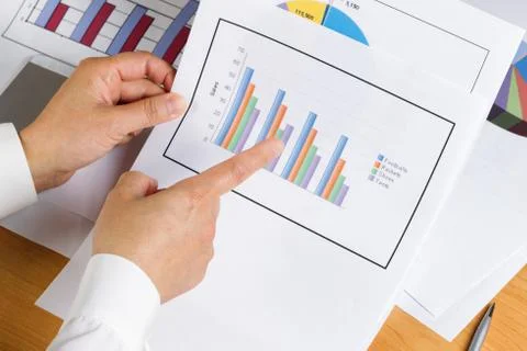 Hand holding bar chart graph while looking at financial data Stock Photos