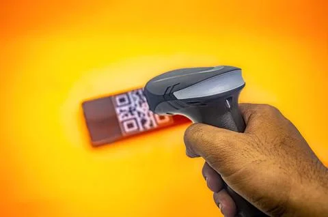 A hand holding a barcode scanner, scanning a QR code on a smartphone agains.. Stock-Fotos