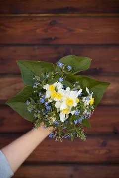 Hand holding a beautiful bunch of spring and summer flowers on wooden table Stock Photos