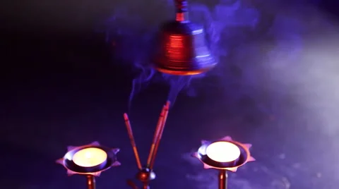 Hand holding bell on dark blue background with red light filter and incense 스톡 동영상 59641264