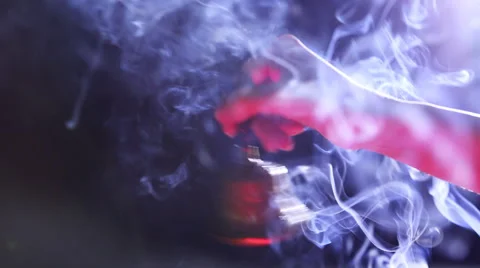 Hand holding bell on dark blue background with red light filter and incense Stock Footage 59641284