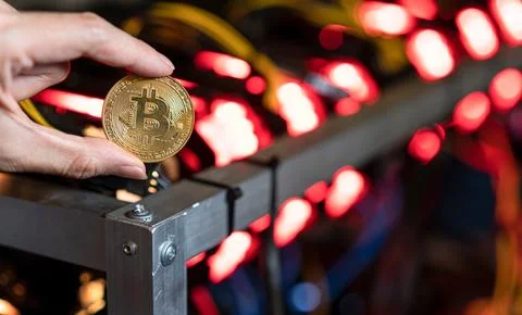 Hand holding bitcoin on Bitcoin mining farm background Stock Photos