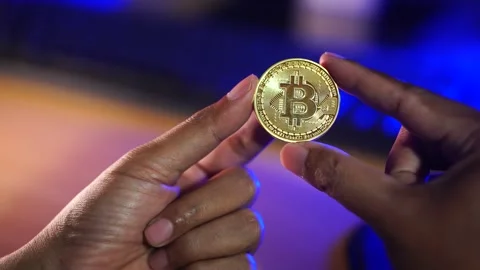 Hand Holding Bitcoin Cryptocurrency Coin with Blue Technology Background Stock Footage 335687067