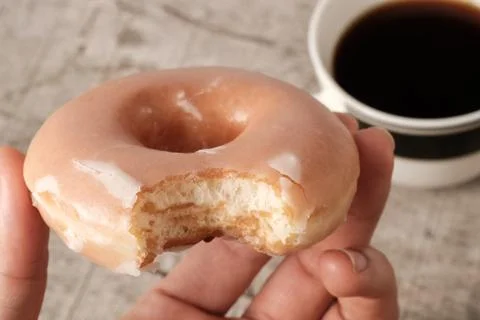 Hand holding bite missing glazed donut Stock Photos