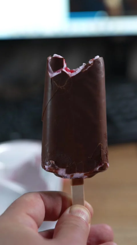 A hand holding a bitten chocolate covered ice cream bar Stock Footage 332781004