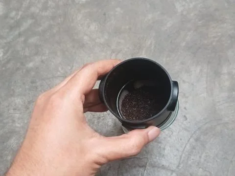 Hand holding black drip coffee filter over glass cup Foto stock