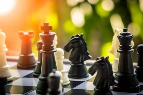 Hand holding Black king attack white king of chess battle on board. Photos
