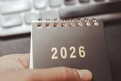 A hand holding a black notepad featuring the year 2026, part of a visual context Photos