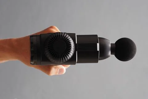 Hand holding black percussion message gun. top view. Stock Photos