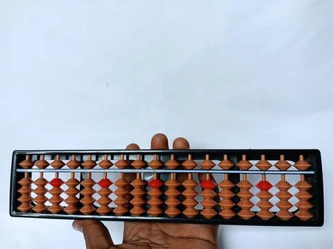 Hand holding black plastic abacus with brown and red rows of beads. Stock Photos