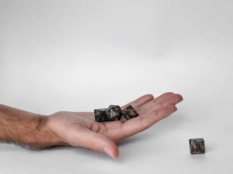 Hand holding black polyhedral dice against a light background Stock Photos