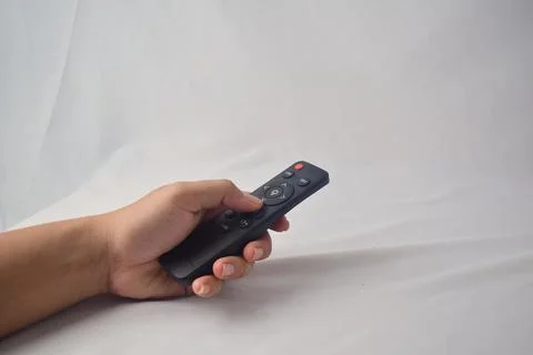 Hand holding black remote control with red power button on white background.. Stock Photos