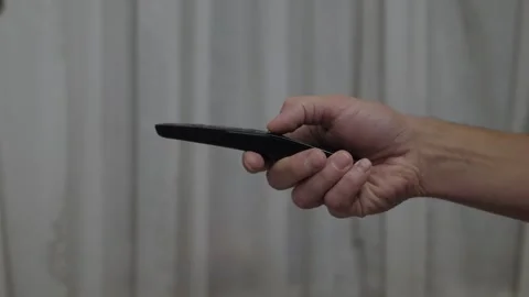 Hand holding black remote Stock Footage 327680892