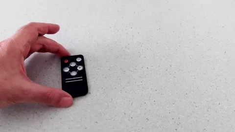 Hand Holding Black Remote on Speckled Countertop, Close-Up Shot Vídeos de archivo 318710153