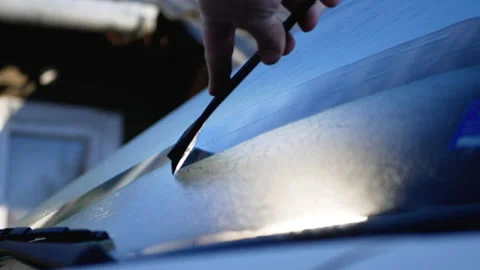 Hand holding black scraper and removing ice or snow from car window Stock Footage 165861900