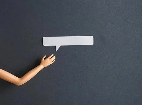 Hand holding blank speech bubble on dark wall background Stock Photos
