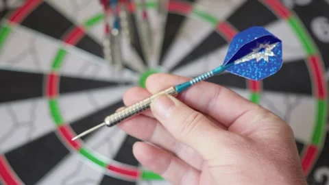 A hand holding a blue dart, preparing to throw it at a dartboard, symbolizi.. Video stock 318468969