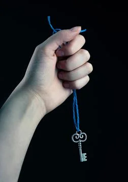 Hand holding blue string with silver key attached 스톡 사진