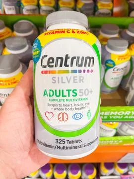 A hand holding a bottle of Centrum Silver Adults 50+ complete multivitamin ta 스톡 사진