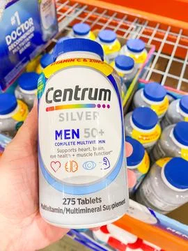 A hand holding a bottle of Centrum Silver Men 50+ complete multivitamin table Foto stock