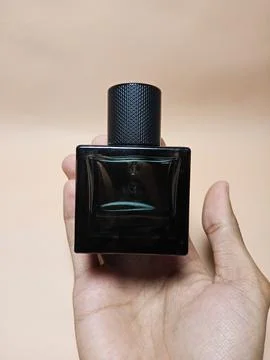 A hand is holding a bottle of perfume Stock Photos