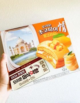 A hand holding a box of Orion Choco Pie Mango Lassi limited edition snacks .. 库存照片