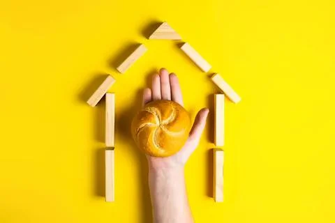 Hand holding bread in house shape made of wooden blocks Stock Photos