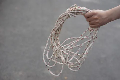 Hand holding a bundle of white utility rope with red threads against a blurred b Stock Photos