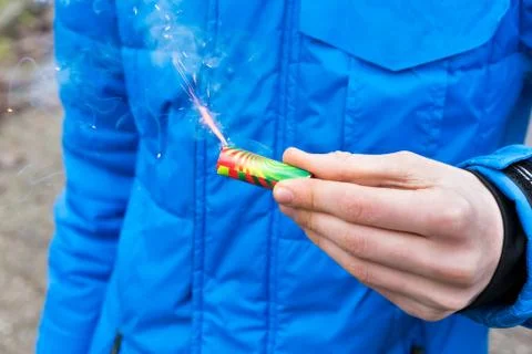 Hand holding burning firework in front of blue jacket Stock Photos