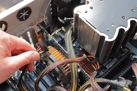 Hand holding a cable fixing a computer Stock Photos