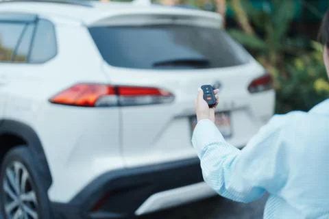 Hand holding car remote control, smart key to lock or unlock  back door  of.. Stock Photos