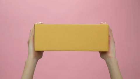 Hand holding cardboard boxes on light pink background. 스톡 동영상 153963907