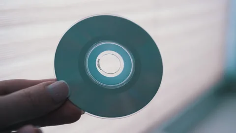 Hand Holding CD-ROM on blurred background Stock Footage 312011206