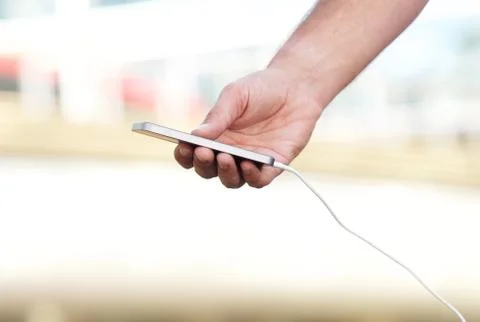Hand holding cellphone with cable Foto stock