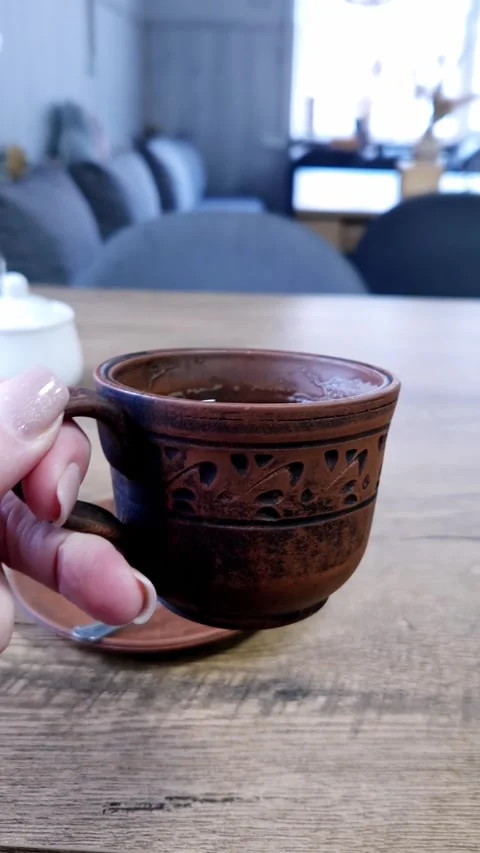 Hand Holding Ceramic Cup of Black Coffee Over Wooden Table in Cafe Stock Footage 338994986
