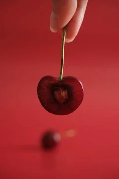 Hand holding a cherry on red background Stock Photos