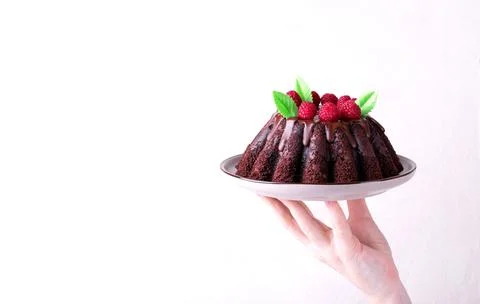 Hand holding chocolate cake with raspberry Foto stock