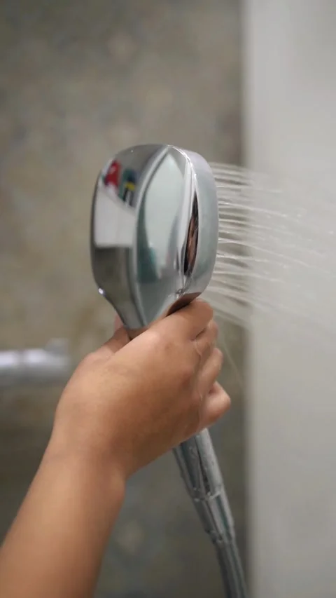 Hand holding chrome shower head with water spraying out Video stock 331771966