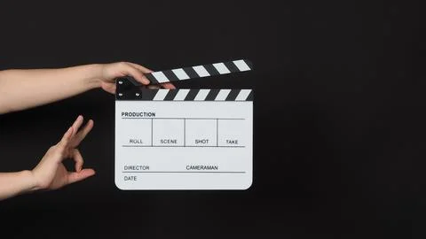 Hand is holding clapper board or movie slate on black background.Other hand.. Stock Photos