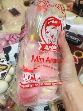 A hand holding a clear plastic package of traditional pink snacks available.. Stock Photos