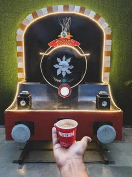 Hand holding coffee cup in front of train display Stock Photos